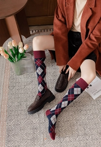 Detailed close-up of argyle knit knee-high socks in navy and burgundy with loafers