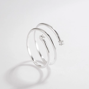 Macro detail of silver ring featuring a spiral design with two clear sparkling gemstones