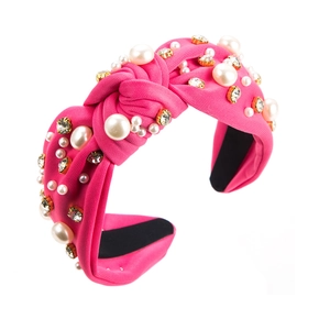 Detail eines rosa Stoff-Stirnbands mit Knoten, weißen Perlen und funkelnden Strasssteinen