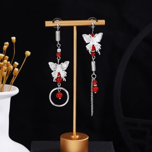 Detail of asymmetrical butterfly drop earrings with red beads and long silver tassels