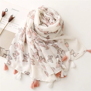 Detail of pink butterfly print and bicolor tassels on a soft white cotton linen scarf