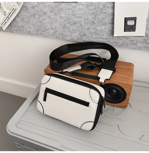 Minimalist white PU leather crossbody bag featuring black piping and a wide shoulder strap
