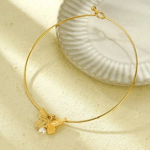 Elegant gold butterfly choker necklace with white pearl pendant on textured background