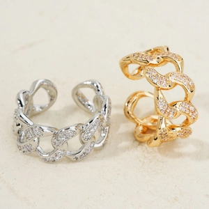 Dual-tone gold and silver chain rings with micro-pave cubic zirconia on sand background