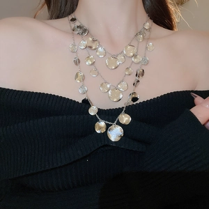 Close-up of triple-layered silver necklace with textured round metal sequins on model