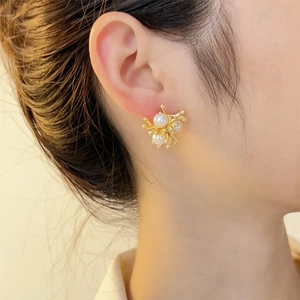 Elegant golden branch-shaped pearl earrings on model with refined artistic floral design