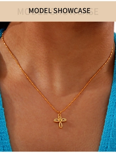 Close-up of a gold-plated cross necklace with rhinestones on a model showcasing the fit