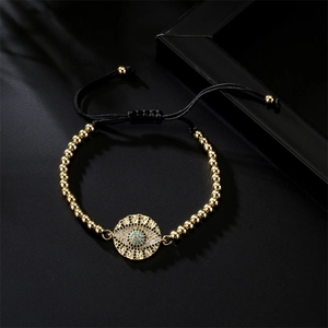 Macro shot of an adjustable woven bracelet featuring a gold zircon evil eye charm