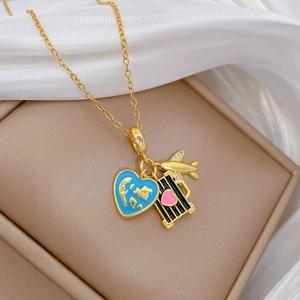 Close-up of gold travel necklace featuring blue enamel globe, suitcase and airplane charms