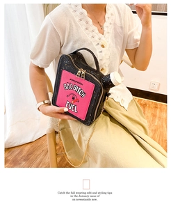 Macro shot of creative oil drum bag featuring pink letter patches and gold chain strap