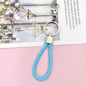 Close-up of blue braided leather keychain with silver metal ring on pink background