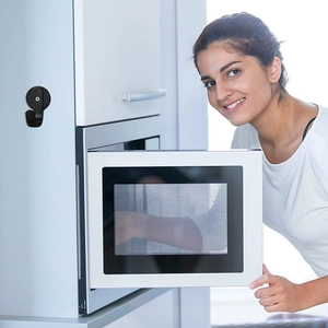 Close-up of black magnetic hook installed on a white microwave in a modern kitchen setting