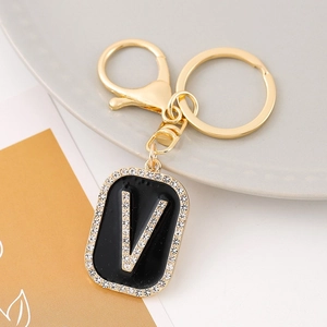 Detailed view of luxury gold letter V keychain with black enamel and crystal accents