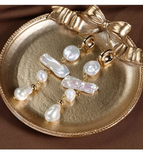 Macro detail of French vintage baroque pearl drop earrings on a retro golden tray
