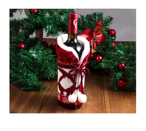 Close-up of a red and white knitted wine bottle cover with decorative white pom-poms