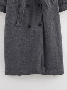 Detail view of double-breasted dark grey wool coat featuring textured fabric and belt