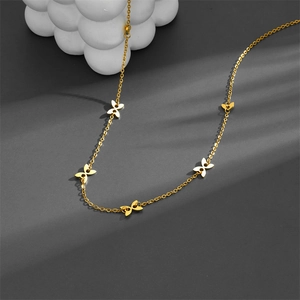 Collier ras du cou doré avec plusieurs petits pendentifs papillon sur fond gris chic