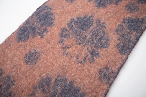 Close-up of soft coral orange woven fabric with elegant blue floral jacquard pattern