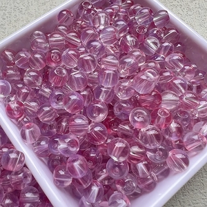 Vue macro de perles en verre translucides rose et violet pour création de bijoux DIY