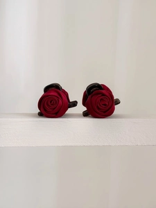 Close-up of elegant red rose hair clips with satin texture on a white shelf