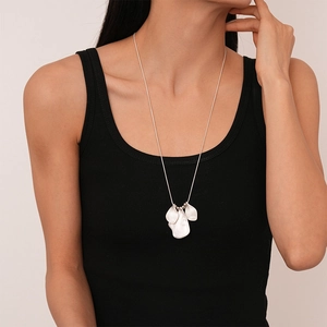 Minimalist long silver sweater chain with textured irregular petal pendants on black top