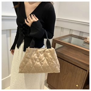 Close-up of beige quilted tote bag with diamond stitching and soft padded texture