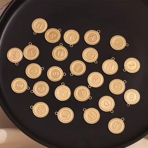 Macro shot of 26 gold striped alphabet charms on a black tray for DIY jewelry making