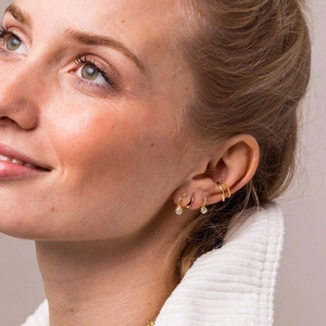 Elegant 5-piece gold earring set with clear crystals and cuffs worn by a model
