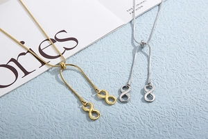 Detail of gold and silver snake chain necklaces with infinity symbol pendants on blue background