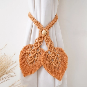 Detail of leaf-shaped cotton curtain tieback with wooden bead and tassels in orange brown