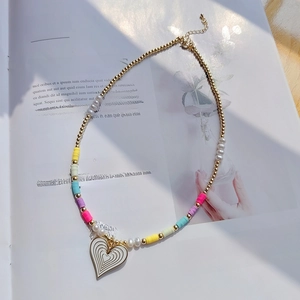 Detail of bohemian beaded necklace with white heart pendant on a magazine background