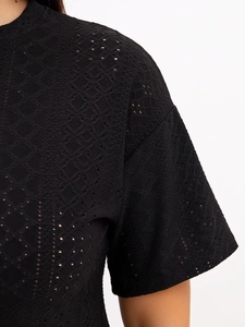 Detail of black eyelet embroidery fabric on women's pajama set with geometric patterns