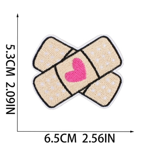 Makro-Detail von beigem Pflaster-Stickerei-Aufnäher mit rosa Herz und Abmessungen