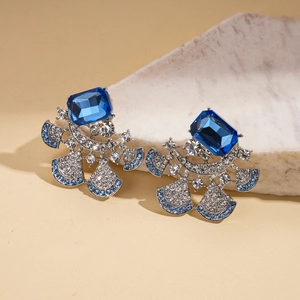 Detail view of silver fan-shaped earrings with large blue gemstone and sparkling rhinestones
