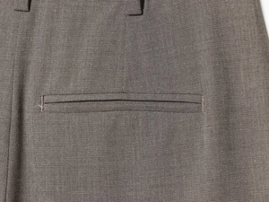 Detail of the back welt pocket and belt loops on dark grey formal suit trousers