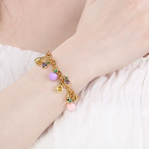 Golden stainless steel bracelet with colorful fruit pendants on female model wrist