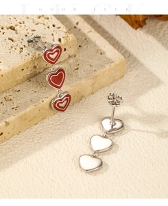 Macro detail of S925 sterling silver long earrings with three red enamel hearts