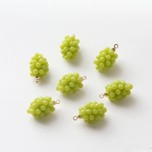 Macro view of seven green resin grape charms with gold hanging loops for DIY jewelry