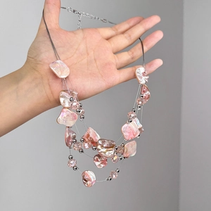 Collier multicouches bohème avec perles de coquillage roses et détails argentés