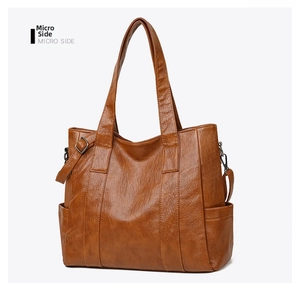 Detailed side view of brown faux leather tote bag showing grainy texture and side pocket