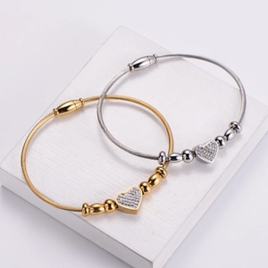 Gold and silver heart cable wire bracelets with shimmering rhinestones on textured tile