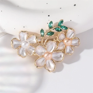 Elegant floral brooch with enamel pearls and green crystals on a luxury gold-tone branch