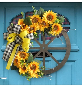 Close-up of sunflower wreath on rustic wooden wheel with decorative ribbon bows