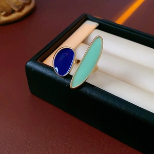 Detailed macro view of geometric gold ring with blue and mint green enamel drop oil