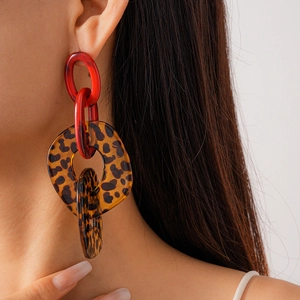 Primo piano di orecchini a catena in acrilico con stampa leopardata e rossa su modella