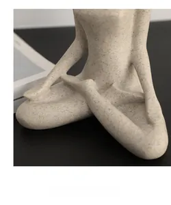 Dettaglio della statuina yoga in arenaria che mostra curve e texture della pietra