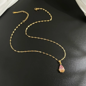 Détail du collier goutte d'or avec pierre rose et motif de fleurs ajourées