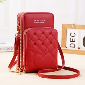 Detailed view of red quilted crossbody phone bag with triple zippers and heart patch