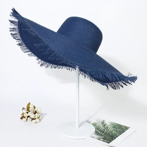 Detailed view of dark blue wide-brim woven straw sun hat with frayed edge on a metal stand