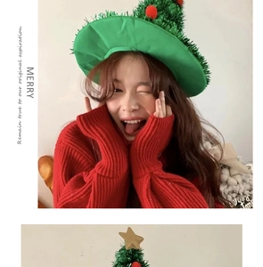 Close-up of green knitted Christmas tree hat with red pom-poms and gold star topper